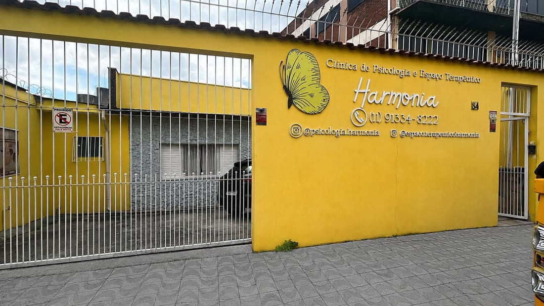 Fachada amarela da Clínica Harmonia, com o logo da borboleta no muro